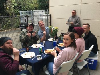 A group of people sit around a table with a blue cloth eating thanksgiving food