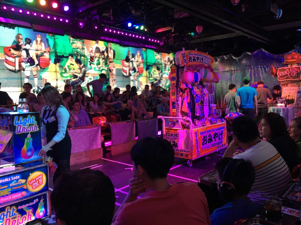 A basement area with low lighting, a projector screen, and concession stands.