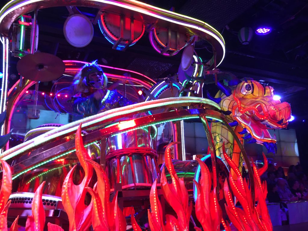 A dragon float outlined in neon lights with a singer on top