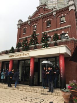 The entrance building to the Christmas market. The brick building has 3 red columns and several christmas trees on the roof