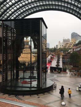 A grand chandelier in a glass case at the end of a red carpet walk