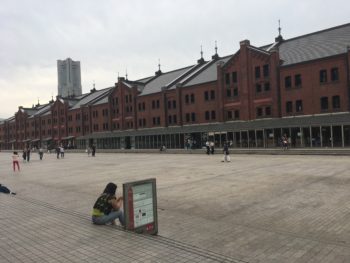 A red brick warehouse stands on the far side of a concrete walkway