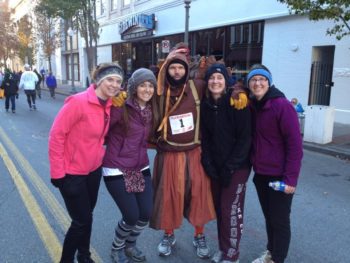 Four young women pose in the street with a man dressed in a turkey costume