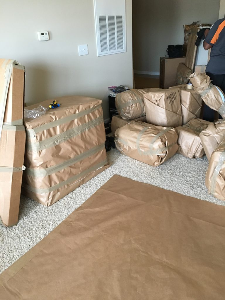 Items wrapped in brown paper stacked and waiting to be loaded on the moving truck