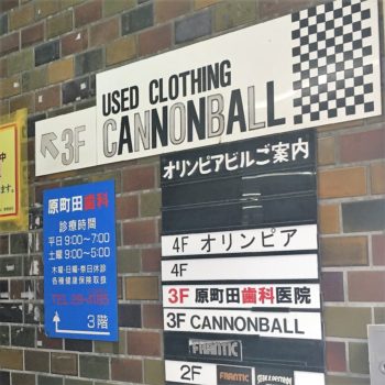 A black and white exterior sign for Cannonball used clothing store is attached to a brick wall and directs shoppers to the third floor