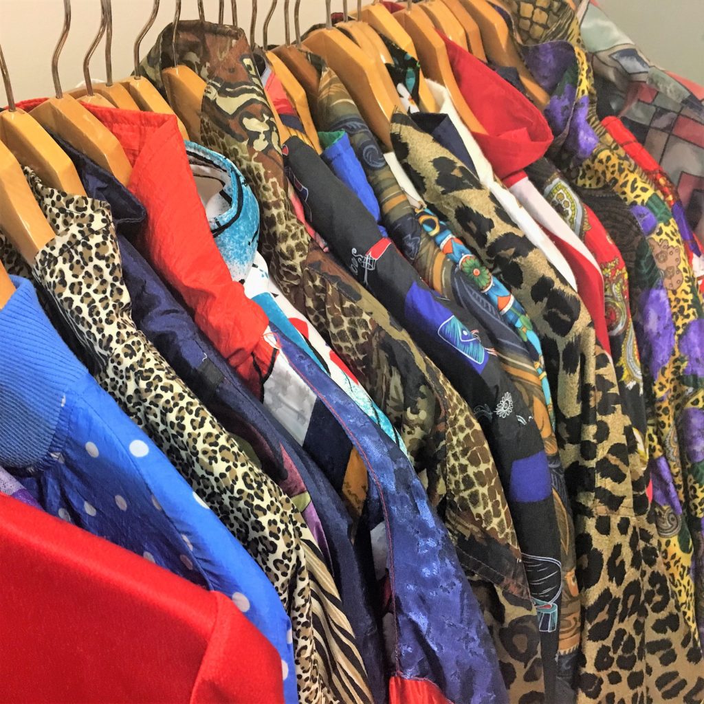 Funky, brightly colored and patterned jackets hang on a clothing rack outside the thrift store Desert Snow